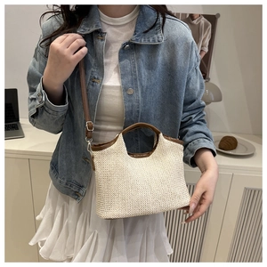 Detail of contrast stitch bucket bag with brown leather handles on white woven texture