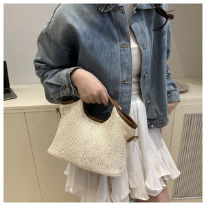 Detail of contrast straw bucket bag with brown leather handles and side metal hook