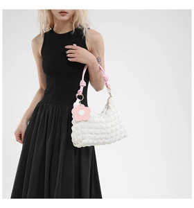 Close-up of white bubble fabric handbag with pink rope handles and flower charm detail