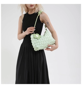 Detail of light green bubble textured fabric shoulder bag with floral charm decoration