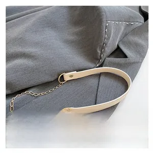 Detail of cream leather shoulder strap with gold metal chain and rivet hardware