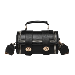 Black barrel bag with rivets, gold swivel lock and colorful geometric woven strap