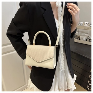 Gros plan sur le motif tressé crème et les détails dorés de ce petit sac à bandoulière