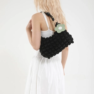 Fashionable black quilted puffer shoulder bag with green flower charm and knotted strap