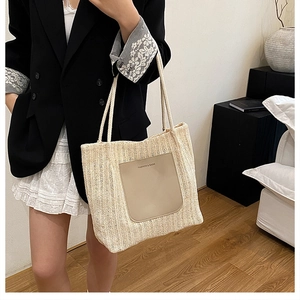 Détail du sac cabas en paille tressée avec écusson en cuir et poignées en corde d'été