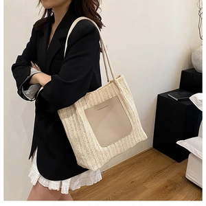 Detail view of woven straw tote bag featuring faux leather pocket and rope strap on model