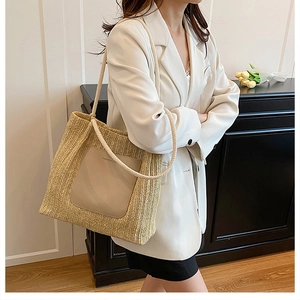 Detail of woven straw tote bag featuring beige leather patch and thick cotton rope handles