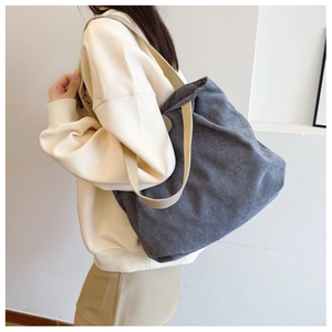 Detailed close-up of the grey corduroy fabric texture and soft strap on a tote bag