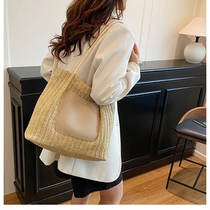 Detail of woven straw tote bag with leather patch and rope straps for summer beach use