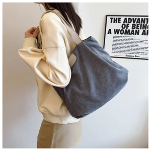 Detail of gray corduroy tote bag featuring leather shoulder strap and fashion label