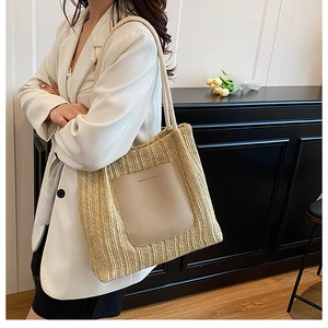 Detail of woven straw tote bag with a khaki leather pocket and braided shoulder straps