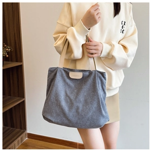 Detail of grey corduroy tote bag with beige handles and Fashion leather tag on shoulder