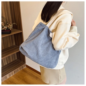 Close-up of blue corduroy tote bag showing soft texture and side logo tag detail