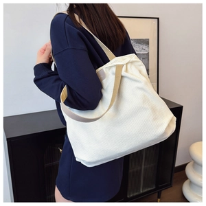 Close-up of off-white corduroy tote bag featuring vertical texture and FASHION leather patch