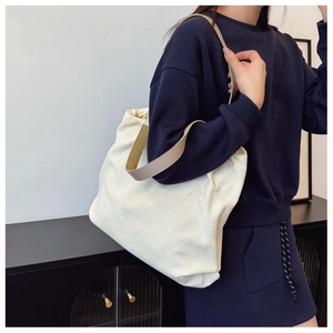 Detail of white corduroy tote bag with brown straps styled on shoulder in daily setting