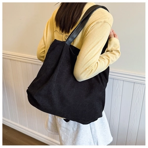 Detail of black corduroy tote bag showing large capacity and durable leather straps