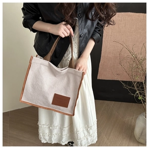 Detailed shot of a corduroy tote bag with fashion leather patch and bicolor handle design