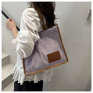 Close-up of purple corduroy tote bag with brown trim and FASHION BAG leather patch