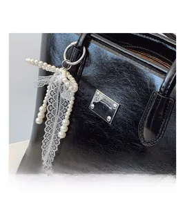 Détail d'un cabas en cuir noir avec un accessoire de charme en dentelle et perles