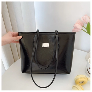 Détail d'un sac cabas en cuir PU noir brillant avec des finitions en argent chic