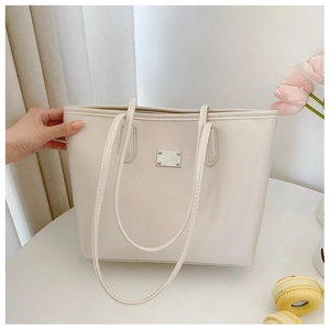 Détail du grand sac cabas en cuir crème avec accent métallique argenté sur table blanche