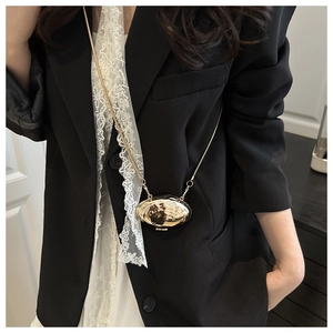 Detail of mini gold shell crossbody bag with artistic hammered texture and metal chain