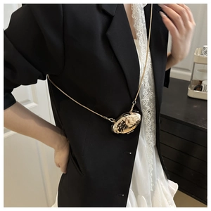 Close-up of a gold shell-shaped mini metal crossbody bag with a sleek chain strap
