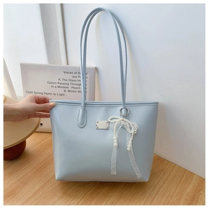 Gros plan du sac cabas bleu clair en similicuir avec pendentif perle et dentelle