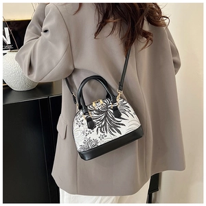 Close-up of contrast floral print shell bag with black leather straps and gold zippers
