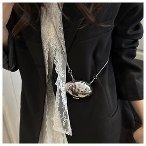 Macro shot of silver hammer-textured mini shell bag with sleek metal chain on black suit