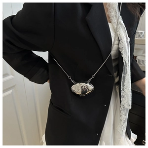 Detail of silver wavy metallic mini shell crossbody bag with a slim chain strap