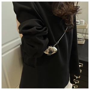 Detail of silver metallic shell mini bag with chain strap styled in an indoor setting