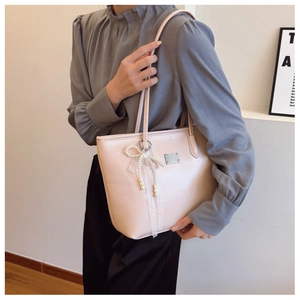 Détail du sac cabas rose en similicuir avec nœud en dentelle et breloque perle