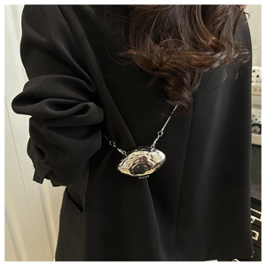 Detail of silver shell-shaped metallic mini bag with a hammered texture on a black suit