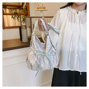 Detail of floral canvas tote bag featuring a blue plaid ribbon bow and magnetic closure