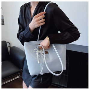 Détail du sac cabas bleu clair avec chaîne en perles et pendentif en dentelle élégant