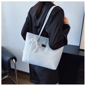 Détail du sac cabas bleu clair avec nœud en dentelle blanche et breloques perles