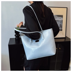 Détail d'un sac cabas en cuir bleu clair avec plaque métallique sur fond minimaliste