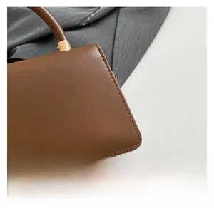Close-up of brown leather handbag featuring precise stitching and gold metal buckle