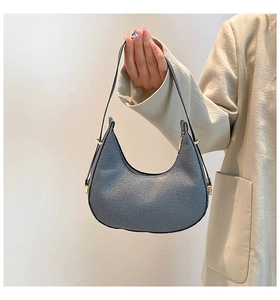 Detail der grauen Hobo-Tasche mit goldenen Beschlägen, von einem Model getragen