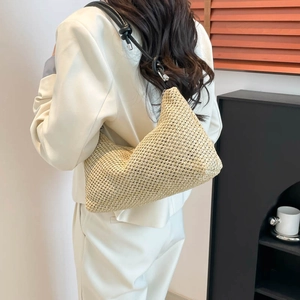 Handwoven straw tote bag with black knotted leather strap and minimalist hobo design