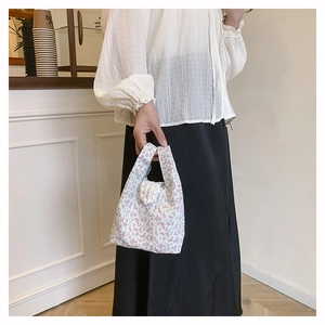 Detailed shot of floral fabric bag with delicate white lace trim and purple patterns