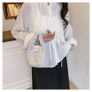Detail of floral bucket bag with white lace trim and delicate cotton handle design