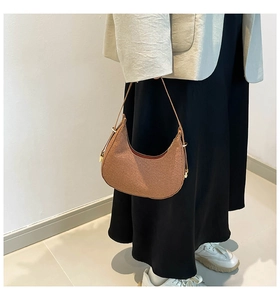 Detail einer braunen Hobo-Tasche mit gewebter Textur und goldenem Schnallenverschluss