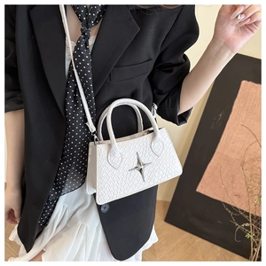 Detail of white crocodile pattern square bag with silver star accent on model