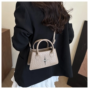 Detailed view of apricot textured leather handbag with silver cross star metal ornament