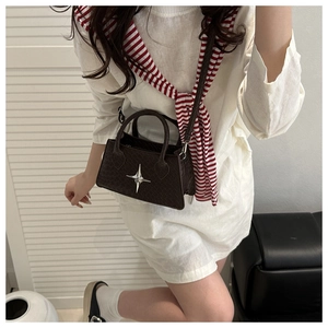 Detailed view of dark brown textured leather bag with metallic star buckle and strap