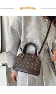 Detail view of dark brown shell bag with geometric prints worn with a grey blazer