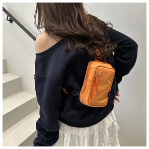 Detail of bright orange lightweight nylon sports mini backpack with textured fabric finish
