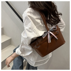 Brown leather tote bag featuring a decorative pink ribbon and checkered bow detail
